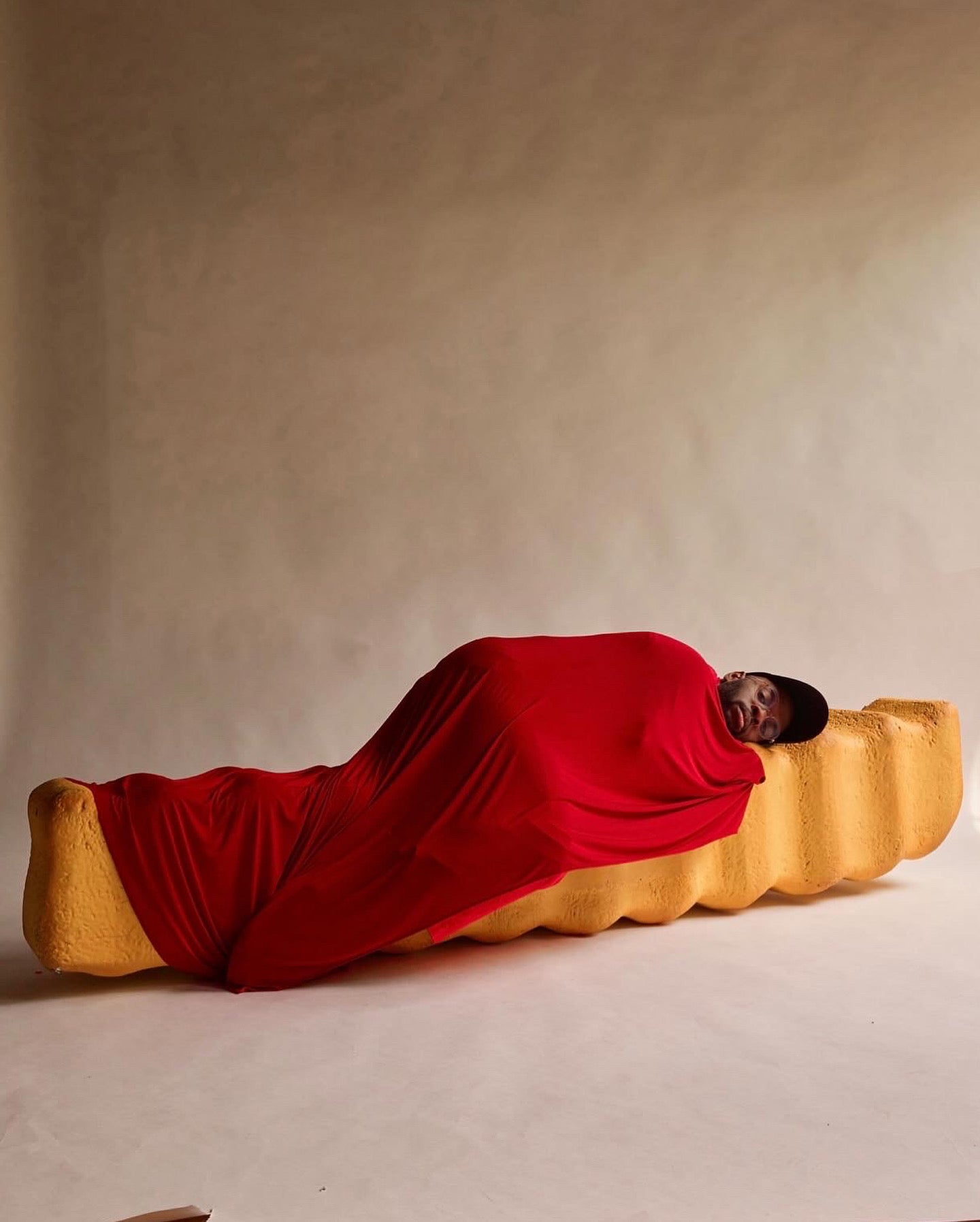 Paul Octavious wrapped in red on a yellow bench